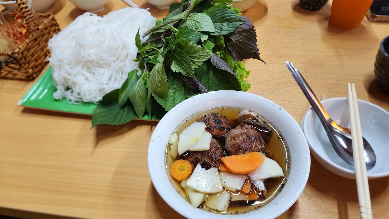 The generous portion of grilled pork and noodles is served in a bowl of tangy-sweet fish sauce, true to the authentic Hanoi style 
